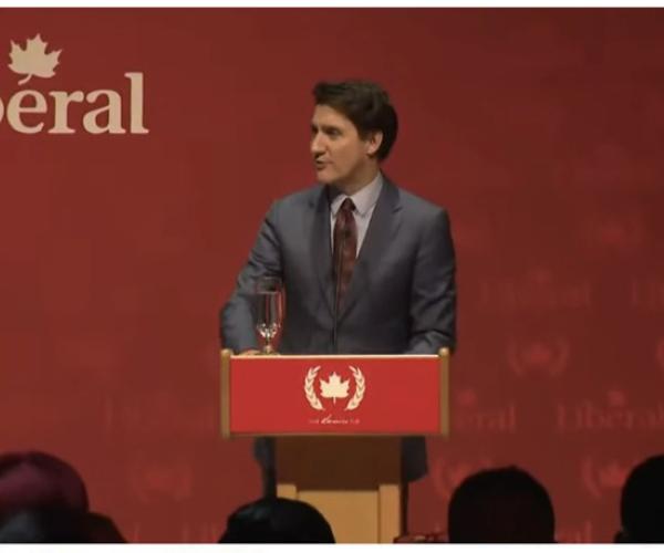 Canada's Prime Minister Trudeau standing at a dias emblazoned with a communist symbol