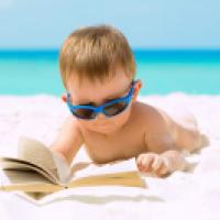 Young boy on the beach reading a book